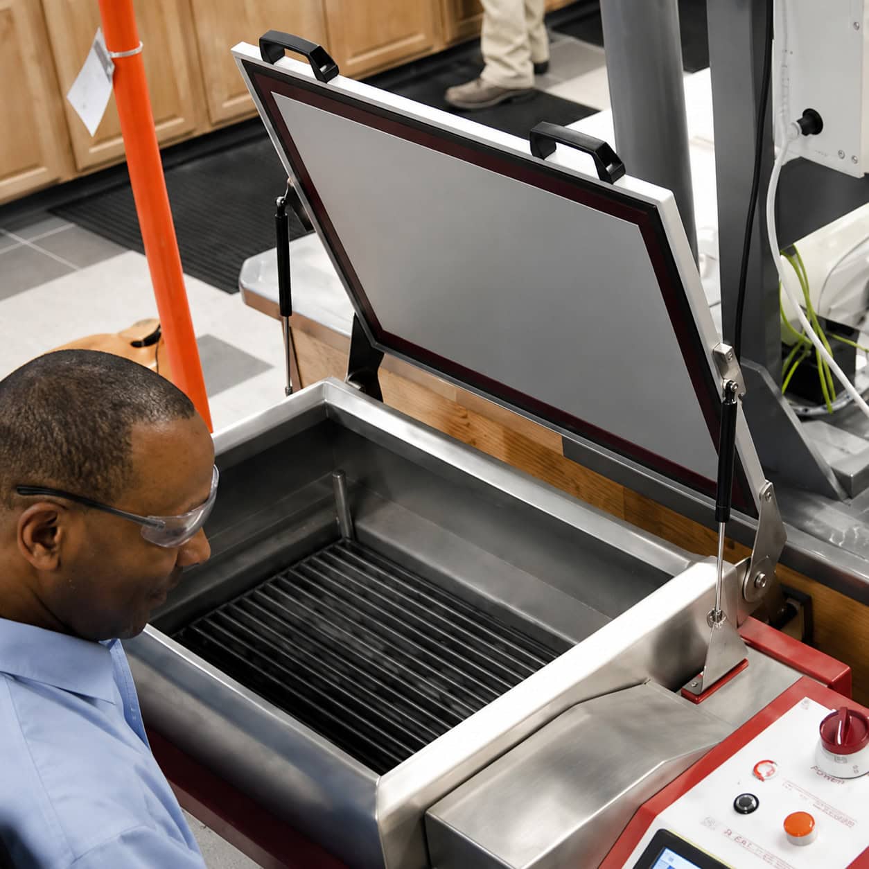 Technician inspecting a water absorption boil test tank for porcelain tile certification